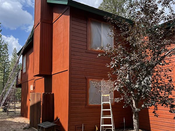 Residential painting and deck staining project in El Dorado County Placer County by Dowell's Painting Back view of a two-story cabin with new paint and deck finish